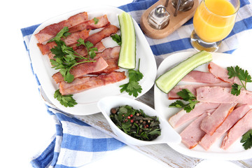 Bacon on plates on napkin on board isolated on white