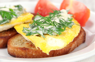 Scrambled eggs and toast on plate on napkin on wooden table