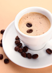 Cup of coffee with coffee beans on beige background