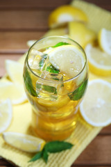 Iced tea with lemon and mint on wooden table