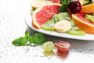 Assortment of sliced fruits on plate with drops