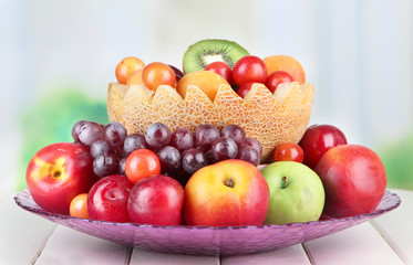 Assortment of juicy fruits on wooden table, on bright