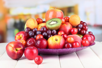 Assortment of juicy fruits on wooden table, on bright