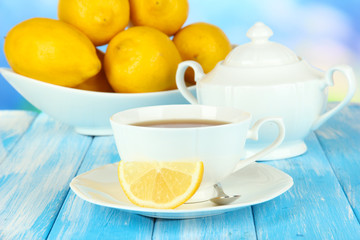 Cup of tea with lemon on table on blue background