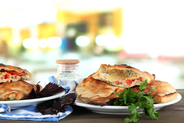 Pizza calzones on plates on table on room background