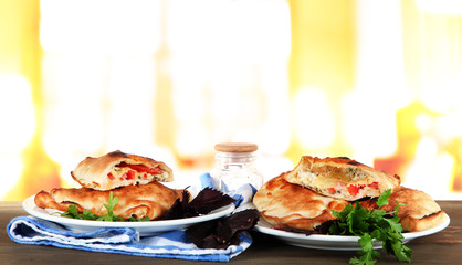 Pizza calzones on plates on table on room background