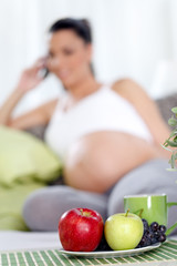 Pregnant woman with fruit on table