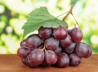 Ripe delicious grapes on table on bright background