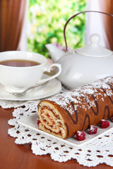 Sweet roll with cup of tea on table in room