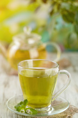 Cup of herbal tea with fresh mint flowers on wooden table