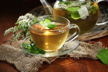 Cup and teapot of herbal tea with fresh mint flowers