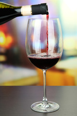 Red wine being poured into wine glass, on bright background