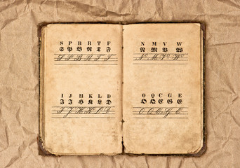 open antique alphabet book over grungy background