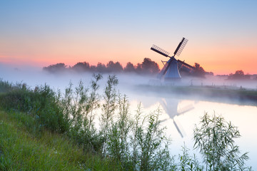 charming Dutch windmill by river - Powered by Adobe