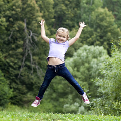 Happy little girl jumping in summer day