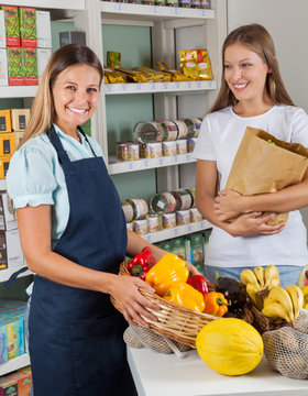 Saleswoman Holding Vegetable Basket With Female Customer