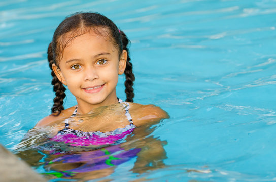 Portrait of happy pretty mixed race child by side of pool 