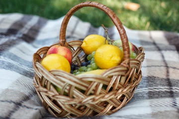 Ripe juicy fruits in basket on wooden table
