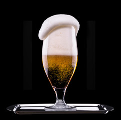 Frosty glass of light beer on black background