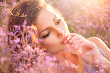 Beauty Girl Lying on a Meadow with Violet Flowers