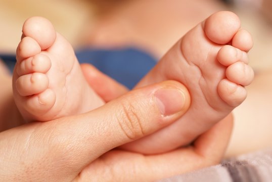 Mother is holding her baby´s feet
