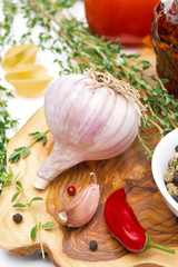 fresh garlic, thyme and chili peppers on a wooden board