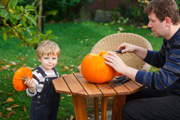 Fototapeta premium Young man and toddler boy making halloween pumpkin