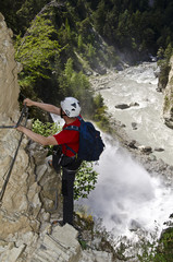Hiker climbing a spectacular via ferrata near a waterfall