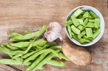 Green beans, potato and garlic, on a wooden table