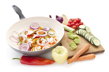 Fresh vegetables on the cutting board and in pan on white