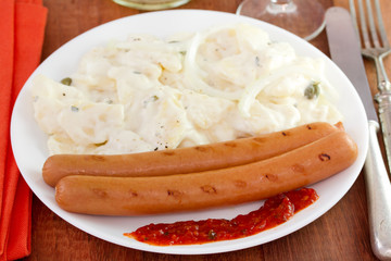 grilled sausages with sauce and salad on the plate