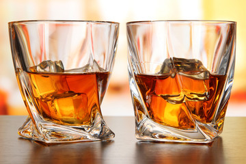 Glasses of whiskey, on bright background
