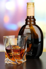 Glass of liquor with bottle, on dark background