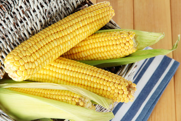 Crude corns in basket on napkin on wooden table