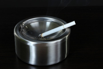 Metal  ashtray with cigarette, isolated on black