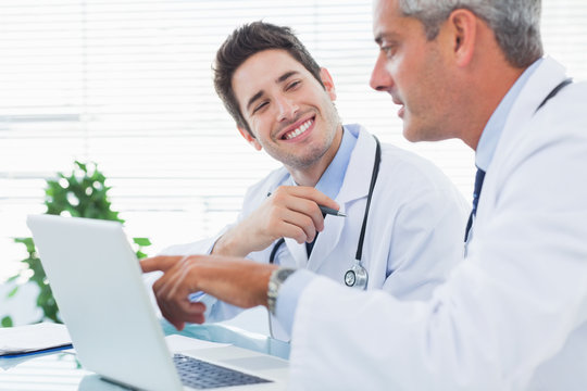 Doctors talking together about something on their laptop