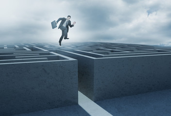 Businessman leaping above a maze