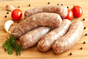 Uncooked sausages with vegetables on the chopping board