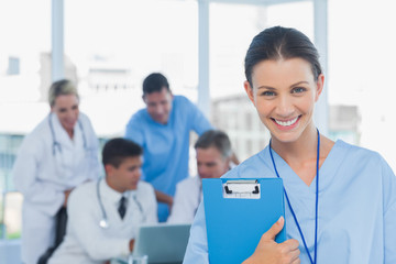 Fototapeta premium Cheerful young surgeon posing with colleagues in background