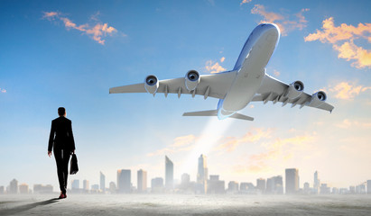 Business woman looking at airplane in sky