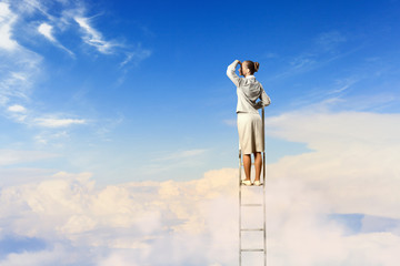 Businesswoman standing on ladder