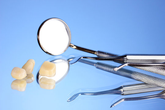 dental mirror with denture teeth on blue background