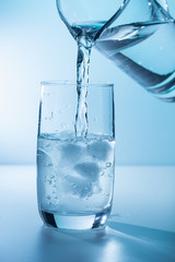 Pouring water into glass with ice