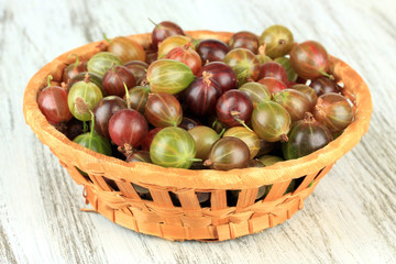Fresh gooseberries in wicker basket on table close-up