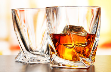 Glasses of whiskey, on bright background