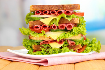 Huge sandwich on wooden table, on bright background