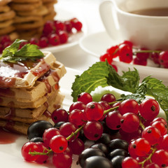 Freshly baked waffles with berries and tea cup