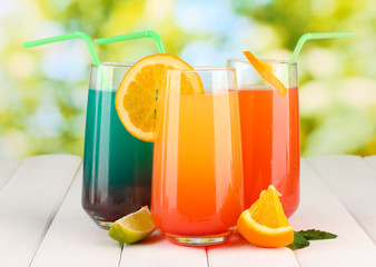 Three cocktails on wooden table on bright background