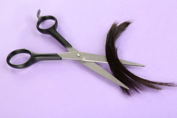 Pieces of hair cut with scissors on purple background