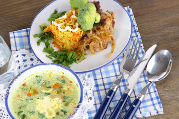 Soup and rice with meat in plates on napkins on wooden table